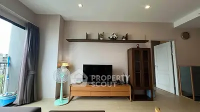 Modern living room with sleek TV stand, wall shelf, and large window for natural light.