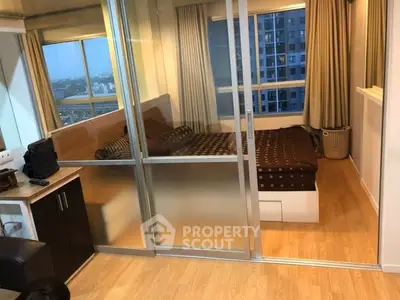 Modern bedroom with glass partition and city view, featuring cozy decor and wooden flooring.
