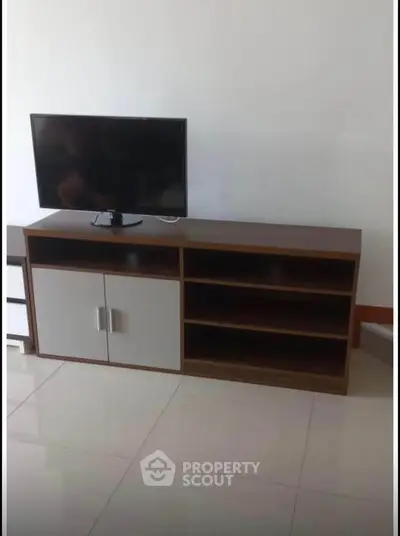 Modern living room with sleek TV stand and flat-screen television on tiled floor.