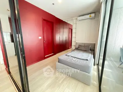 Modern bedroom with red accent wall and sleek design in a stylish apartment.