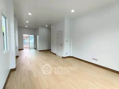 Spacious empty room with wooden flooring and bright natural light