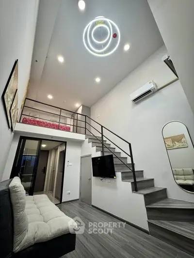 Modern loft apartment with high ceilings and stylish interior design, featuring a mezzanine bedroom and sleek staircase.
