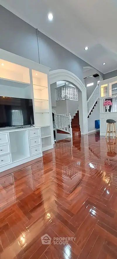 Spacious living room with glossy wooden floors and elegant staircase in modern home