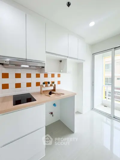Modern kitchen with sleek white cabinets and vibrant orange backsplash, featuring an open layout and natural light.