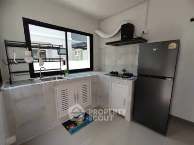 Modern kitchen with sleek black fridge and gas stove in open layout design.