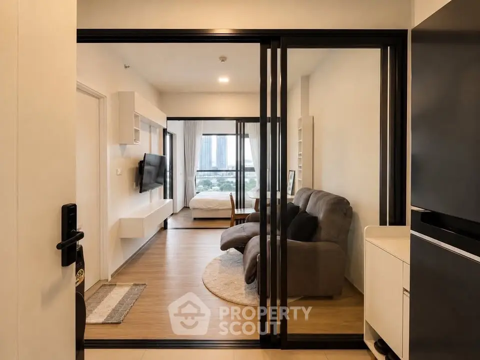 Modern apartment interior with sliding glass doors, cozy living area, and city view from the bedroom.