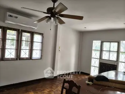 Spacious living room with ceiling fan and large windows, perfect for natural light and comfort.