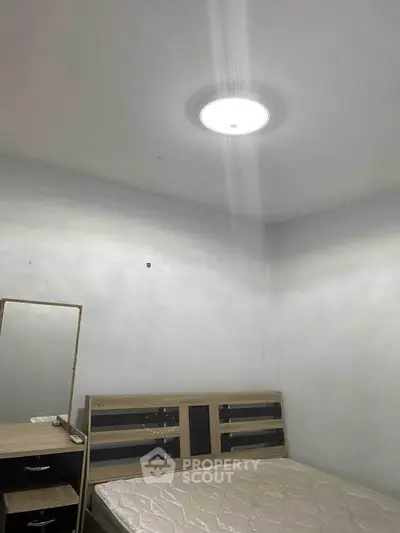 Minimalist bedroom with wooden bed frame and dresser, ideal for cozy living.