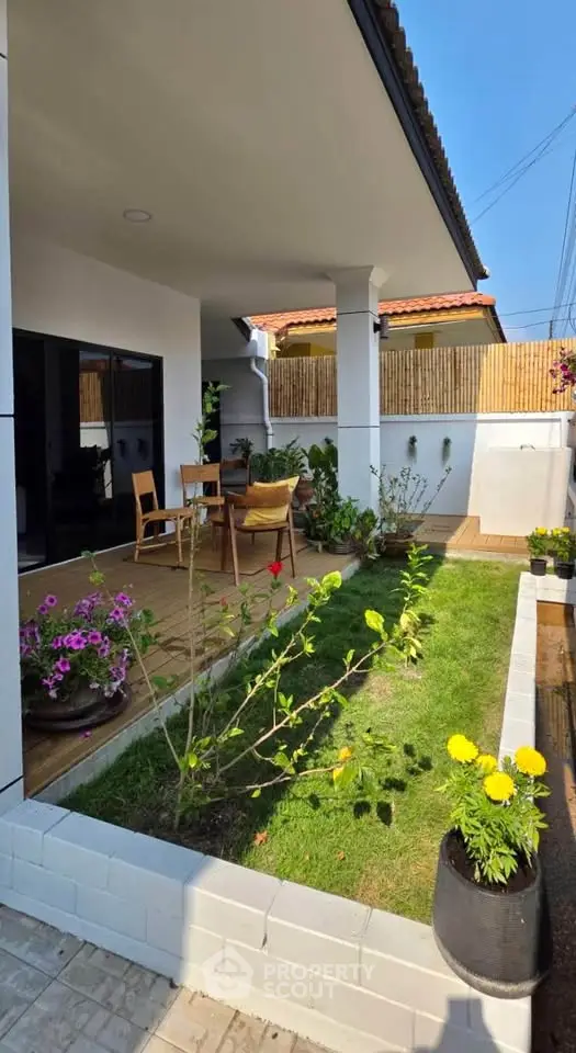 Charming garden patio with lush greenery and cozy seating area, perfect for outdoor relaxation.