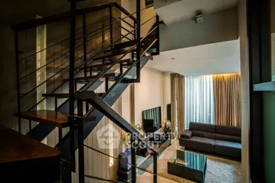 Modern duplex living room with stylish staircase and cozy seating area.