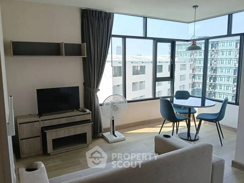 Modern living room with large windows, stylish furniture, and city view in a contemporary apartment.