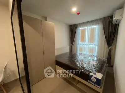 Modern bedroom with large window and sleek furnishings in a cozy apartment.