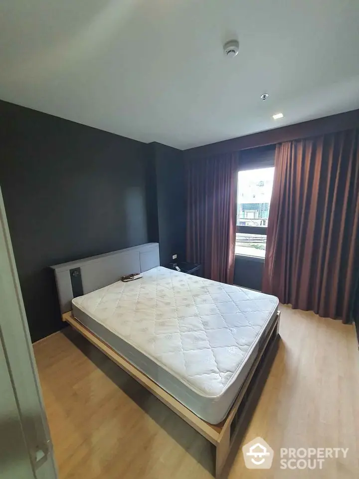 Modern bedroom with minimalist design and large window offering natural light.