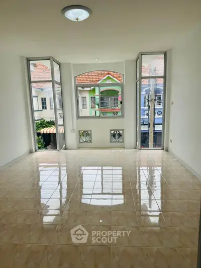 Spacious empty room with large windows offering a charming neighborhood view, perfect for customization.