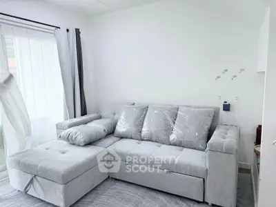 Modern living room with stylish gray sectional sofa and natural light from large windows.