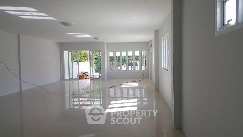 Spacious open-plan living room with large windows and glossy floors, perfect for natural light lovers.