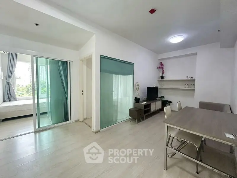 Modern open-plan living room with dining area and sliding glass doors leading to a balcony.