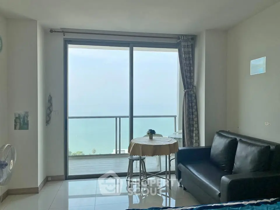 Stunning ocean view from modern living room with balcony access in high-rise apartment.