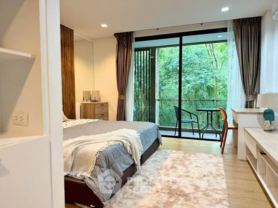 Luxurious bedroom with balcony view of lush greenery, featuring modern decor and cozy ambiance.