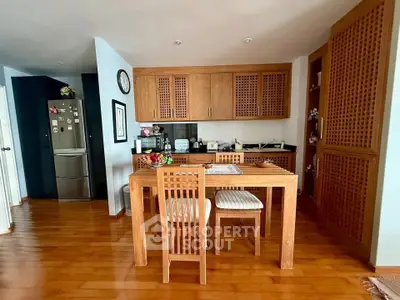 Charming kitchen with wooden cabinetry and dining set, featuring modern appliances and warm wooden flooring.