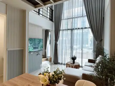 Spacious modern living room with high ceilings and large windows, featuring elegant decor and abundant natural light.