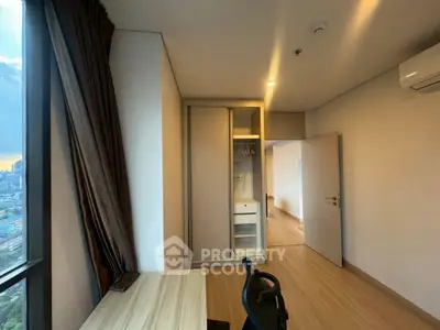 Modern bedroom with city view, featuring sleek wardrobe and workspace.