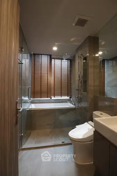 Modern bathroom with glass shower and bathtub, sleek design and natural light.