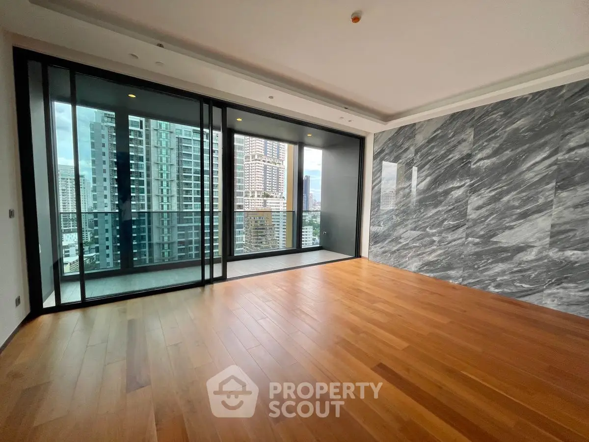 Spacious modern living room with hardwood floors and city view balcony.
