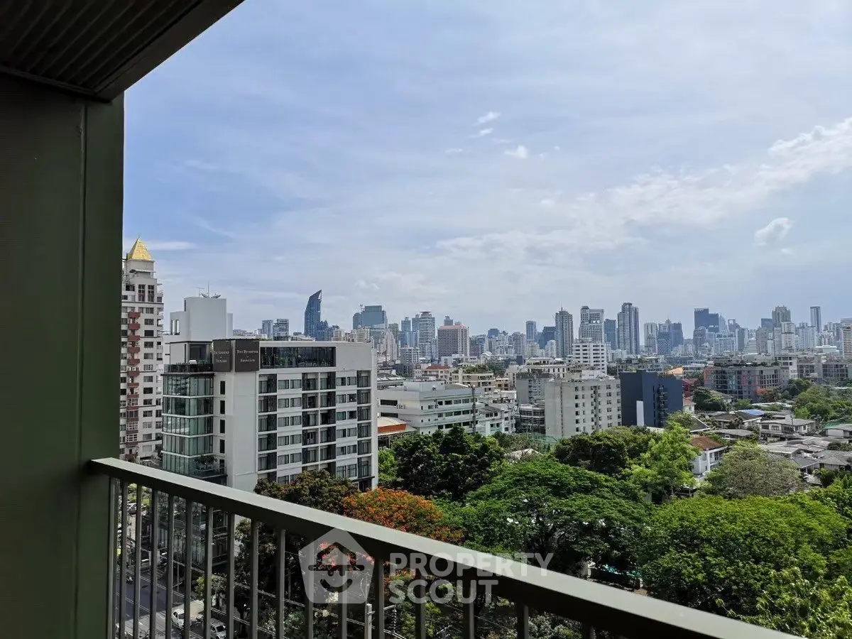 Stunning cityscape view from a high-rise balcony overlooking urban skyline and lush greenery.