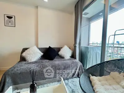 Cozy living room with plush sofa and city view balcony, perfect for relaxation.