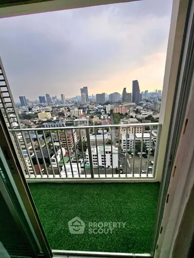 Stunning cityscape view from a high-rise balcony with artificial grass flooring.