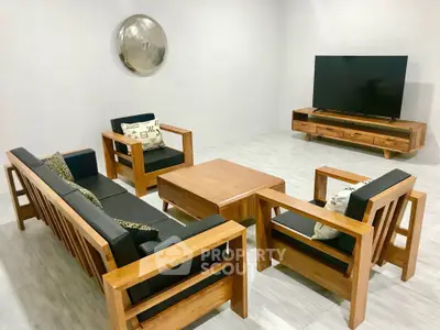 Modern living room with sleek wooden furniture and large flat-screen TV, perfect for relaxation and entertainment.