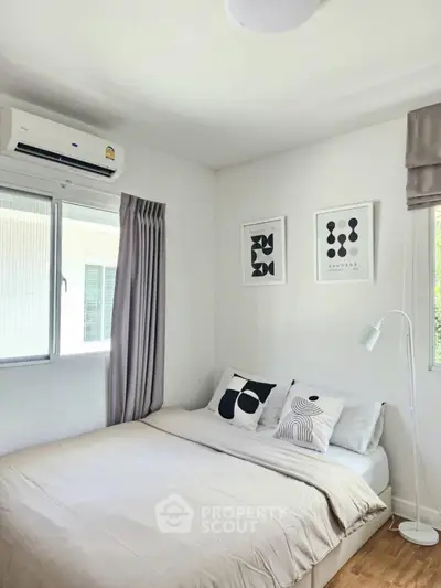 Cozy bedroom with modern decor and natural light, featuring a comfortable bed and stylish artwork.