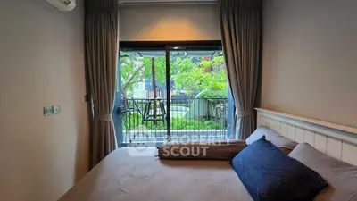 Cozy bedroom with balcony view of lush garden, perfect for relaxation and tranquility.
