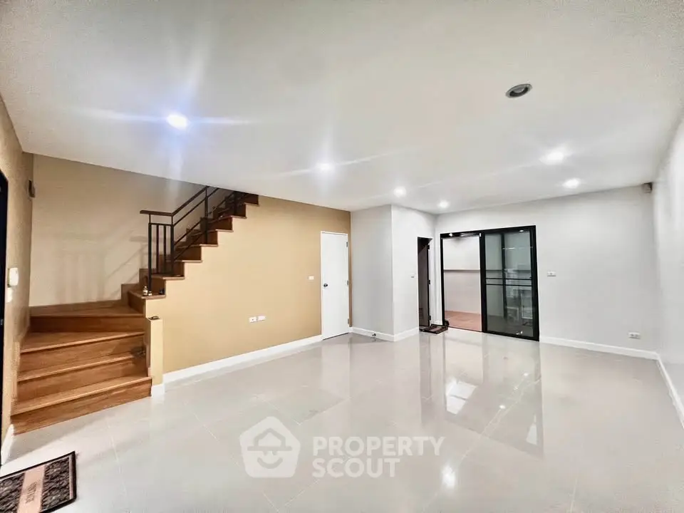 Spacious modern living room with staircase and glass doors, ideal for family gatherings.