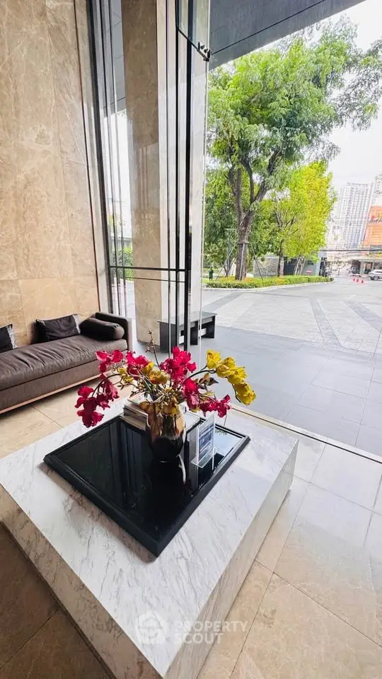 Luxurious building entrance with elegant marble decor and vibrant floral arrangement.