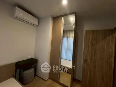 Modern bedroom with mirrored wardrobe and air conditioning unit