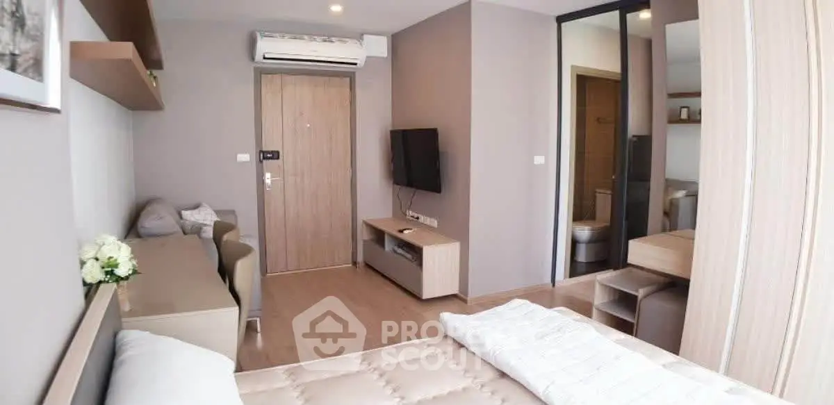 Modern bedroom with neutral tones, featuring a cozy bed, wall-mounted TV, and air conditioning.