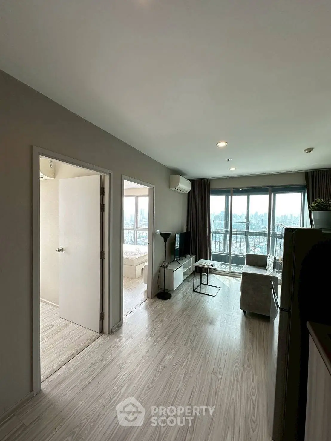 Modern living room with city view and balcony access in a high-rise apartment.