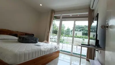 Spacious bedroom with large windows and modern furnishings in a serene setting.