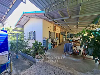 Charming outdoor patio with lush greenery and covered seating area, perfect for relaxation.