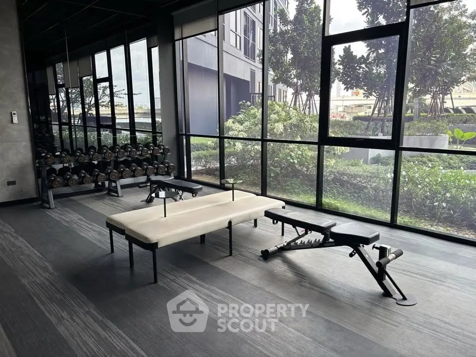 Modern gym with large windows and fitness equipment in a luxury residential building.