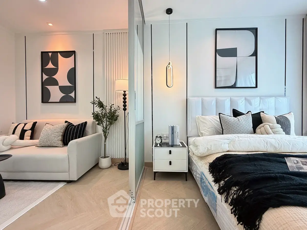 Modern bedroom with stylish decor and cozy living area, featuring elegant artwork and soft lighting.