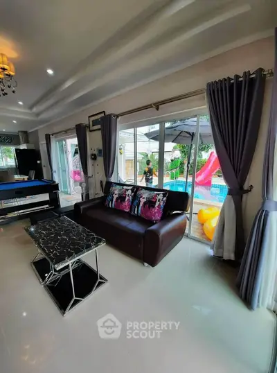 Spacious living room with pool view and modern decor, perfect for family gatherings.