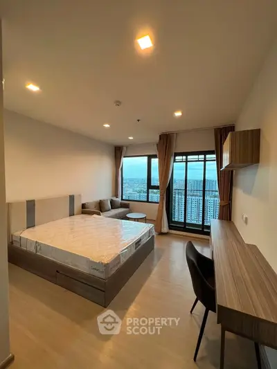Modern bedroom with city view, featuring a cozy bed, stylish desk, and large windows for natural light.