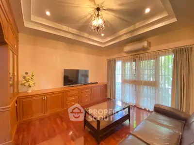 Elegant living room with chandelier, hardwood floors, and large window for natural light.
