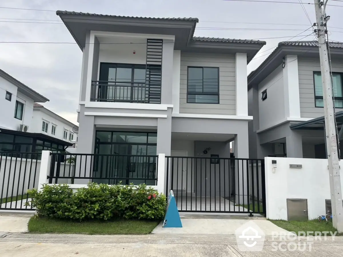 Modern two-story house with sleek design and gated entrance in suburban neighborhood.