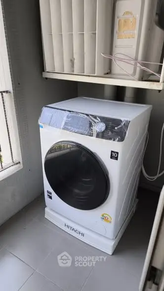 Modern laundry area with a sleek Hitachi washing machine in a compact space.