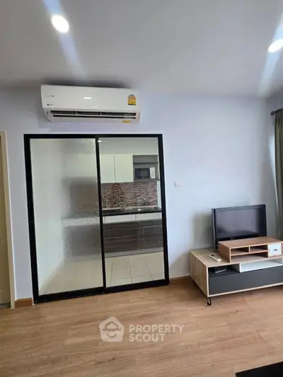 Modern living room with air conditioning and sliding glass doors leading to a stylish kitchen.