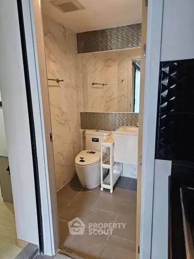 Modern compact bathroom with sleek design and marble accents in a contemporary apartment.